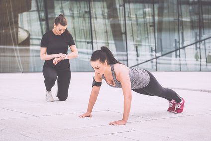 Woman doing push-ups exercises with her personal trainer